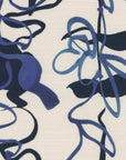 Close-up of grasscloth wallpaper with blue floral line drawings on a textured off-white background.