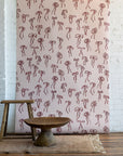 Vintage-inspired wallpaper with hand-drawn red bows on a soft pink background, styled with rustic wooden furniture and a neutral woven rug.