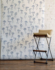 Elegant wallpaper featuring hand-drawn blue bows on a crisp white background, complemented by a beige cushioned stool with black metal legs.