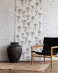 Minimalist silk wallpaper featuring black handdrawn bows on a white background, styled with a black leather and wood chair and a large rustic vase.