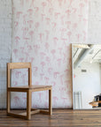 Feminine wallpaper with delicate pink hand-drawn bows on a white background, styled with a natural wood chair and a large mirror reflecting an industrial-style interior.