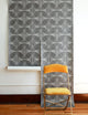Gray geometric wallpaper with curved circular overlapping shapes, featuring delicate dotted texturing and abstract interconnected design, with yellow folding chair in foreground
