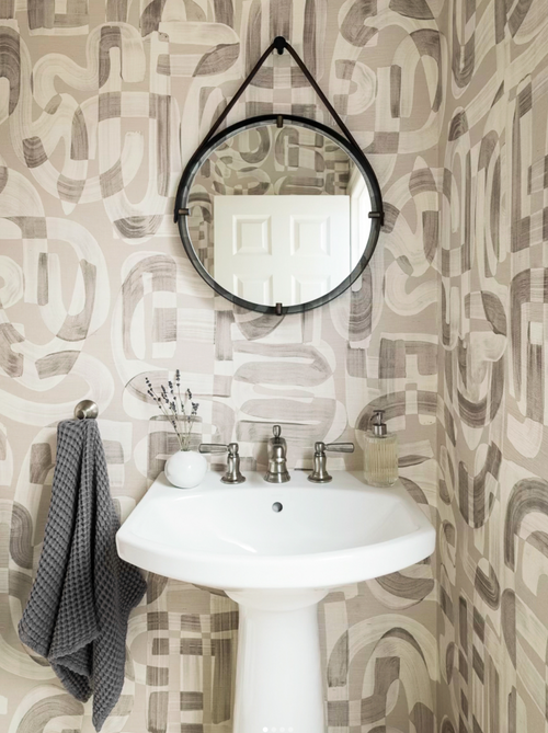 Powder bath with abstract neutral grasscloth wallpaper design Down the Rabbit Hole with white pedestal sink and round black mirror
