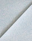 A folded section of blue wallpaper with a delicate, nature-inspired feather motif, highlighting the intricate design.