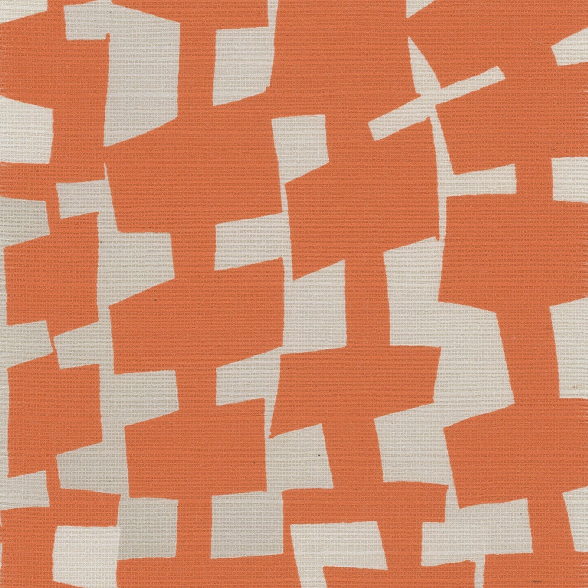 A close-up of geometric-patterned grasscloth wallpaper in bold orange and off-white, showcasing an abstract arrangement of irregularly shaped blocks.