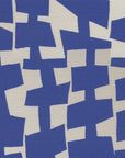 A close-up of geometric-patterned grasscloth wallpaper in deep blue and off-white, with abstract, irregularly shaped blocks forming a bold, contemporary design.