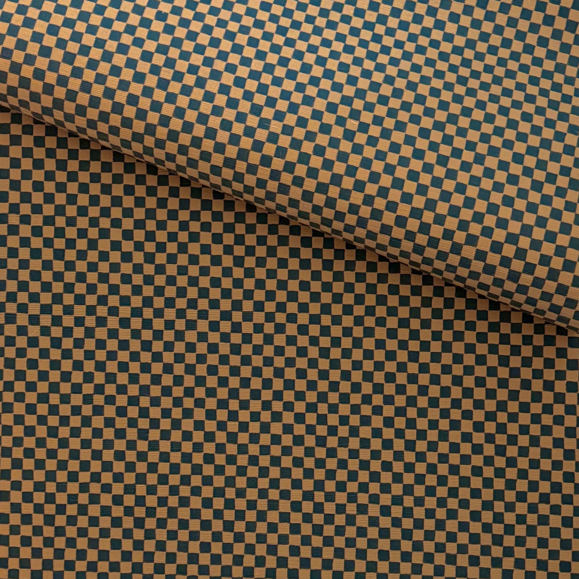 A folded roll of deep brown and black checkered grasscloth wallpaper with a subtle textured finish, giving a classic yet modern aesthetic