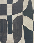 Extreme close-up of black-and-white grasscloth wallpaper, highlighting the bold, abstract brushstroke pattern and textured woven material.