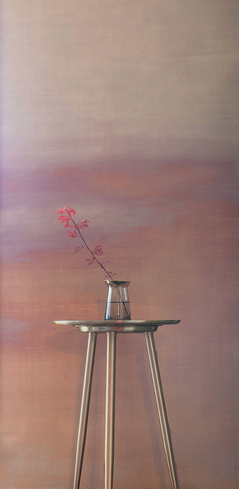 Warm-toned gradient wallpaper in soft mauve and peach hues, creating a sunset-inspired backdrop for a delicate red-leafed branch in a glass vase.