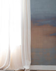 Neutral-toned ombré wallpaper with soft blue and taupe gradients, styled beside airy white curtains in a minimal interior.