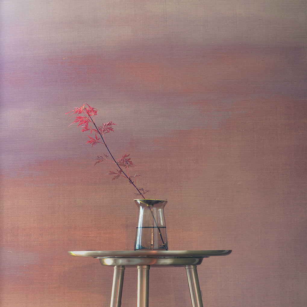 Warm-toned gradient wallpaper in soft mauve and peach hues, creating a sunset-inspired backdrop for a delicate red-leafed branch in a glass vase.