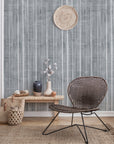 Bohemian-style living room with a deep gray textured wallpaper featuring vertical brushstroke stripes, styled with woven baskets, vases, and a rattan chair.