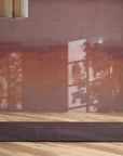 Sunset-inspired wallpaper in rich terracotta and mauve tones with a soft, painted effect, creating a cozy accent wall in a modern living space.