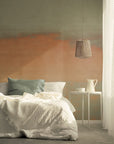 Earthy gradient wallpaper in sage green and warm clay orange tones, styled in a serene bedroom with layered white bedding and soft morning light.