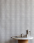 Modern kitchen scene with a minimalist round table and stainless steel accessories set against a light grey plaid wallpaper backdrop.