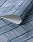 Rolled blue plaid wallpaper with a soft diagonal twill texture, featuring intersecting navy and sky-blue lines for a tailored, textile-inspired look.