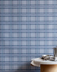 Styled kitchen setting with a marble and cork table against a blue plaid wallpaper, creating a cozy yet modern atmosphere