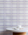 Minimalist kitchen scene with a marble and cork table set against a lavender plaid linen wallpaper, creating a gentle and calming interior look.