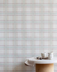 Serene interior scene with a marble and cork table set in front of a pastel plaid wallpaper, creating a light and airy atmosphere.