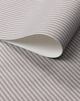 Close-up of folded wallpaper roll with classic charcoal and cream vertical pinstripes, printed on a textured linen.
