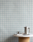 Interior setting with vintage blue and white plaid check wallpaper as the backdrop, styled with a marble and cork pedestal table and stainless steel coffee accessories.