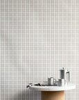 Interior shot of linen vintage plaid check wallpaper in soft neutrals, styled with a marble and cork table and stainless steel coffee accessories.
