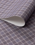 Close-up of vintage plaid check wallpaper in muted lavender and soft taupe tones with a subtle linen-textured finish, shown with a curled edge.