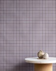 Interior styling with vintage plaid check linen wallpaper in lavender and taupe, paired with a marble and cork pedestal table topped with natural decorative elements.