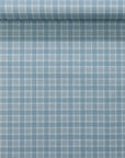 Rolled wallpaper sample highlighting a vintage plaid check pattern in soft blue and white with a natural linen wallpaper.