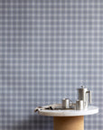 Interior setting with vintage plaid check linen wallpaper in cool gray-blue tones, styled with a marble and cork table and stainless steel coffee set.