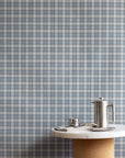 Interior styled with vintage plaid check linen wallpaper in dusty blue and cream, paired with a cork and marble pedestal table and stainless steel coffee accessories.