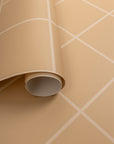 Close-up of a rolled-out beige wallpaper with a white grid pattern, showcasing its textured surface and flexible material.