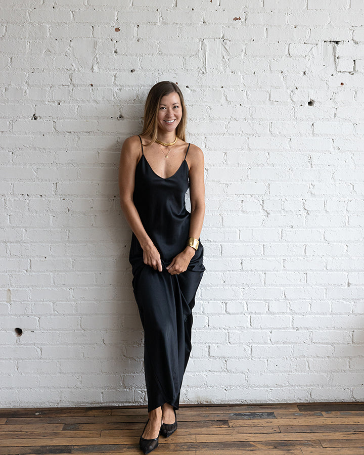 Woman wearing a black outfit standing against a white brick wall.