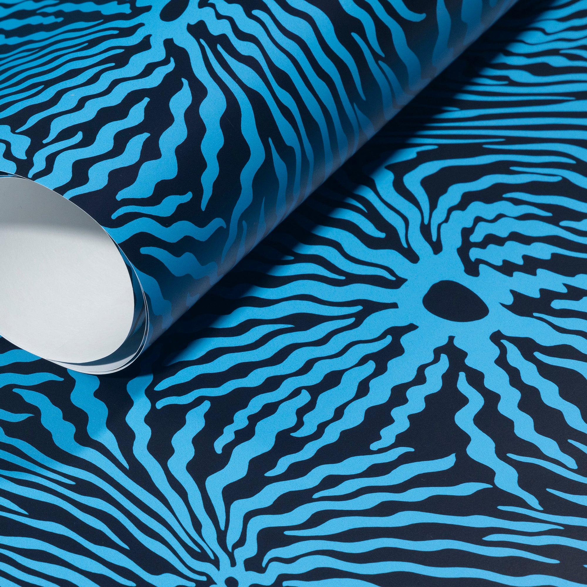 Rolled-up navy wallpaper with striking electric blue wave-like patterns,
highlighting its bold contrast and fluid movement.