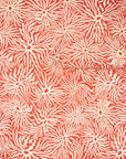 Warm terracotta wallpaper with swirling cream-colored wavy lines radiating from
circular centers, partially unrolled to display the earthy and artistic design.
