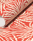 Rolled-up terracotta wallpaper with intricate cream wavy patterns, showcasing its textured, modern appeal.