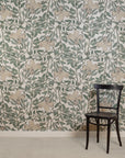 Room with silk wallpaper featuring a delicate botanical design in soft green and beige tones on a white background, depicting hand-painted flowers and leafy vines, complemented by a black wooden chair.