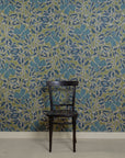 Room with silk wallpaper featuring a bold botanical pattern in deep blue and green tones, showcasing hand-painted flowers and leaves with white outlines, complemented by a black wooden chair in front.