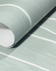 Rolled-up sage green wallpaper with white wavy vertical stripes, showing smooth texture and subtle color variations.