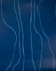 Close-up of navy blue wallpaper featuring free-flowing light blue vertical lines, creating an organic, modern aesthetic.