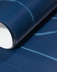 Rolled-up navy blue wallpaper with fluid light blue stripes, highlighting its smooth texture and elegant design.