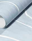 Rolled-up light blue wallpaper with delicate white wavy stripes, emphasizing its smooth texture and contemporary design.