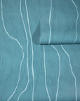 Muted teal wallpaper with abstract white vertical wavy lines, partially unrolled to reveal the organic, flowing pattern