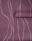 Deep plum wallpaper with soft pink wavy vertical lines, partially unrolled to highlight its rich color and organic pattern.