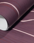 Rolled-up plum wallpaper with soft pink wavy stripes, emphasizing its smooth texture and elegant contrast.