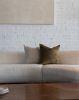 Gold and brown sunburst pillow styled with cream checkerboard pillows on white boucle sofa