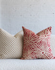 Cream and tan checkerboard pillow styled with red sunburst pillows on white boucle sofa