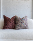 Maroon sunburst pillow styled with deep maroon botanical leaf pillows on white boucle sofa
