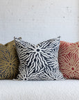 Black and ivory sunburst pillow with gold and red variations on white boucle sofa