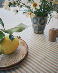 Blue and cream striped linen fabric used as a tablecloth on a nook table set with lemons and ceramics